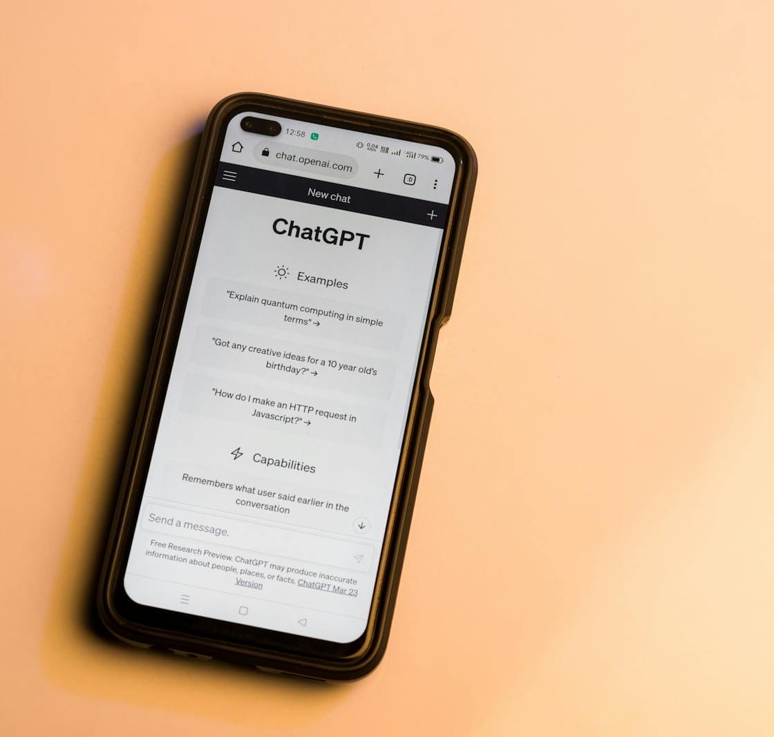 Smartphone showing ChatGPT website with warm tone, highlighting AI technology.