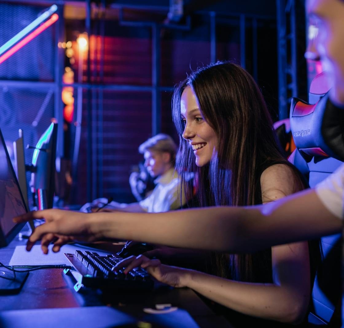 Group of teenagers happily engaged in gaming at a computer setup indoors.
