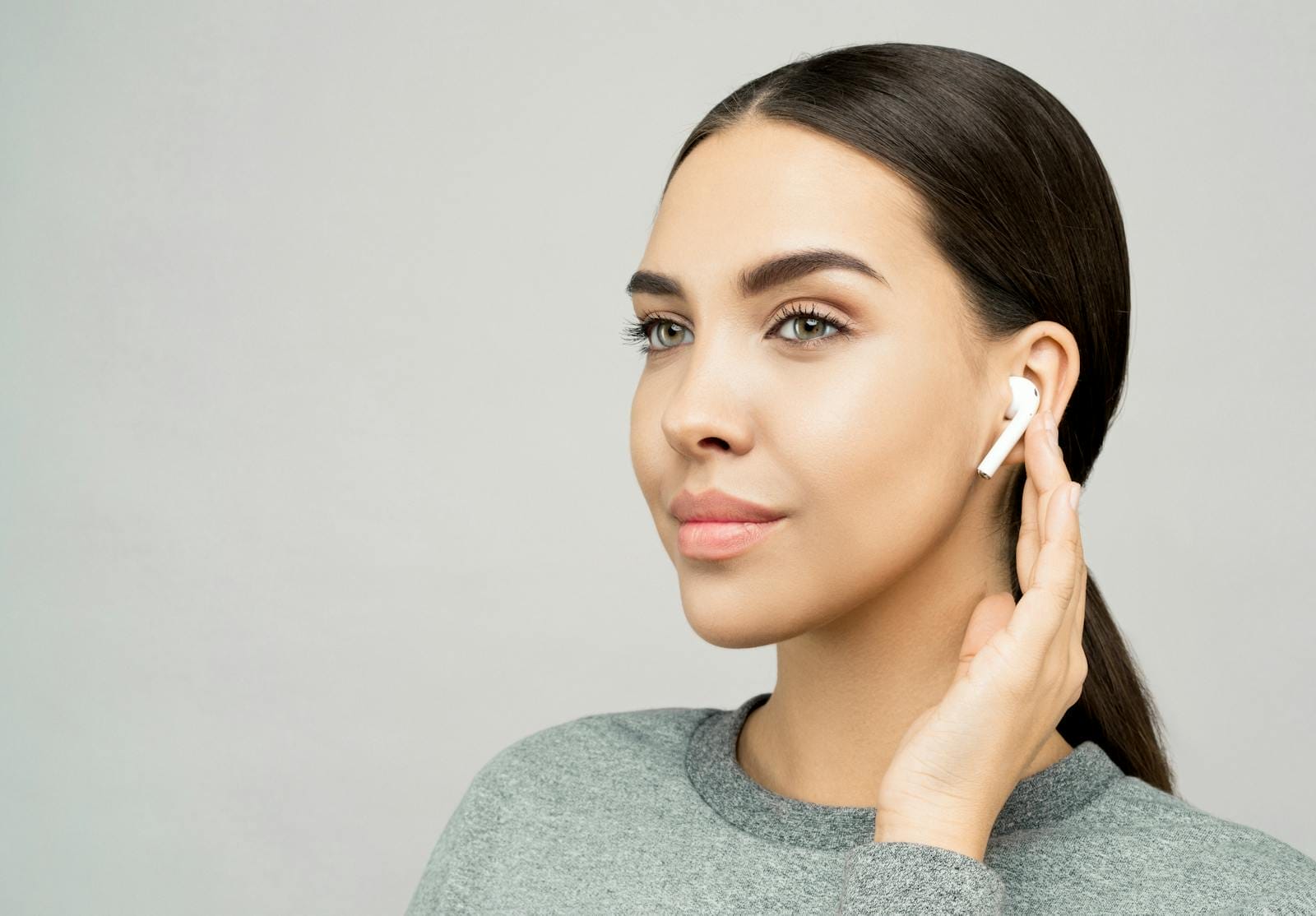 Modern portrait of a young woman wearing wireless earbuds, highlighting style and technology.